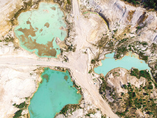 Drone view on a flooded kaolin quarry with turquoise water and white shore. Aerial survey of a kaolin pit flooded with water.
