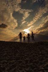 Sunset and family on the sand, silhouettes of people on the beach, success and family unity