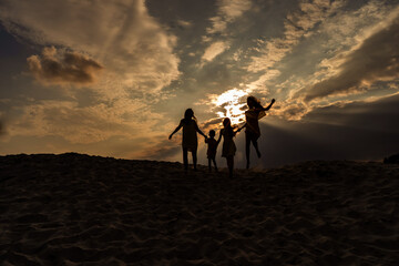 Obraz premium Sunset and family on the sand, silhouettes of people on the beach, success and family unity