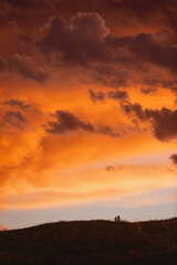 Couple of people on a hill at sunset