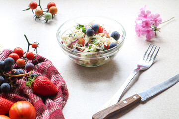 Vegetable salad with grapes in a glass dish on the kitchen table, close-up, top view