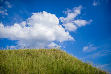 Green hill and blue sky with clouds