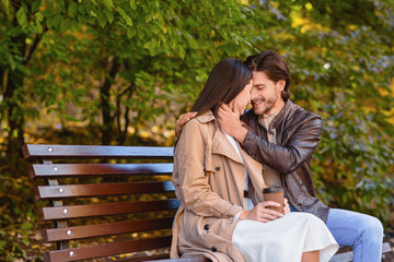 Beautiful romantic couple cuddling on bench at park