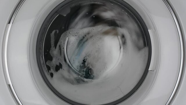 Washing machine washing clothes./ Washing clothes with laundry detergent.