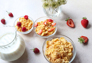 Morning Breakfast of cornflakes and raspberries and strawberries, milk on the kitchen table, side view