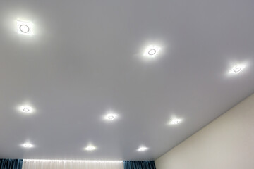 suspended ceiling with halogen spots lamps and drywall construction in empty room in apartment or...