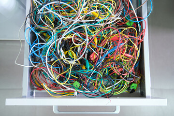 Disorganized colorful cables on a drawer. Messy wires.