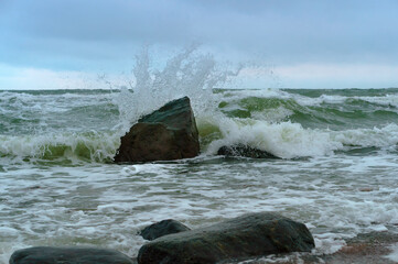 The waves crash on the rocks. Sea coast. Waves and storms at sea. Rocky shore.