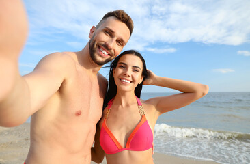 Fototapeta premium Happy young couple taking selfie on beach