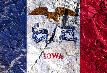 Fototapeta premium The Iowa state flag in the shape of an eagle with a blue ribbon in its beak on the white-blue-red tricolor on the Independence Day on a mountain wall. Rock trail of climbers during the ascent.