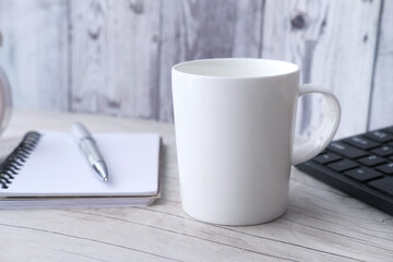  white mug mockup with with keyboard, notebooks on table 