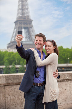 Tourist couple in Paris stop for a picture with the Eiffel Tower