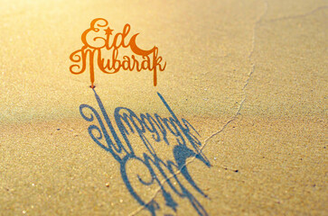 text Eid Mubarak (in English Happy Holidays) on the sand