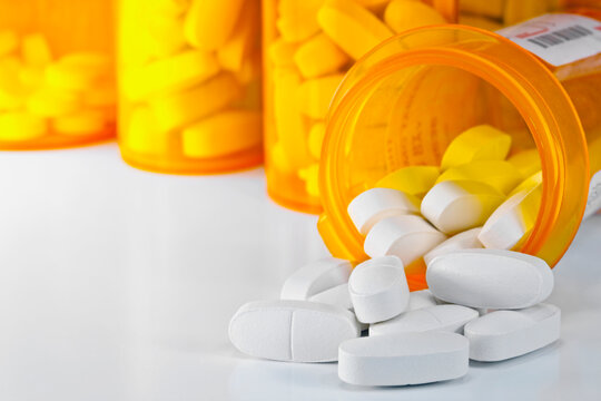 Prescription medication spilling from an open medicine bottle