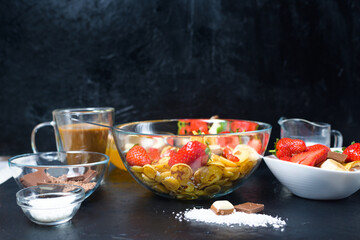 mini pancake cereal bowl with fresh strawberries banana chocolate, coconut shavings and honey in small plates. the view from the top . the trend of self-isolation
