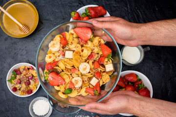mini pancake cereal bowl with fresh strawberries banana chocolate, coconut shavings and honey in small plates. the view from the top . the trend of self-isolation