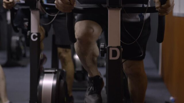 Gym group exercise bike pedaling front panning down - slow motion 60fps