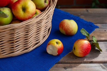 there are 3 apples on the blue tablecloth, one has already been bitten