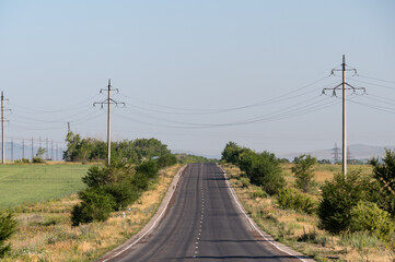 Rough asphalt road with power lines