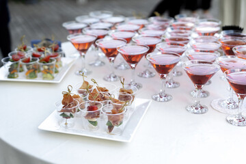 Set of cold snacks, jamon as the main snack. In the background drinks in beautiful glasses.