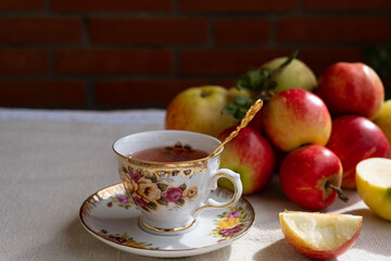 there is a beautiful cup of tea and apples on the table