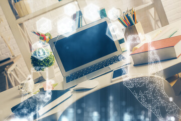 Computer on desktop in office with technology theme hologram. Double exposure. Tech concept.