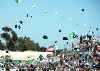 Graduation caps in mid air with crowd shown in background