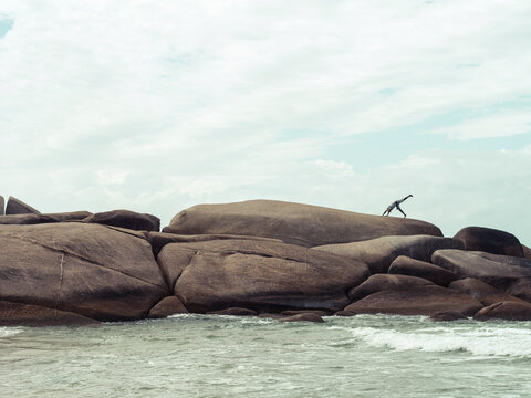 Man exercising on boulders by the beach