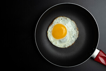 fried egg in black pan and parsley, on black background