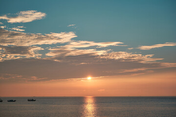 The sunset sea, fishing boats, and the blue sky.