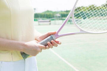 テニスラケットを持つ女性の手元