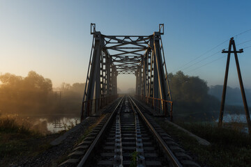 Fototapeta na wymiar Landscape with railway and bridge. Sunrise over the misty river