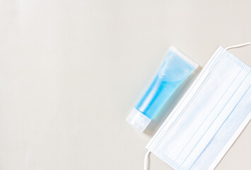 Flat lay, blue alcohol gel tube and medical mask for prevention and disinfection of corona virus. Or wash your hands in hospital or home. Isolated style with gray background and blank space for text.