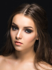 Young pretty female model with sophisticated makeup looking at camera isolated on black.