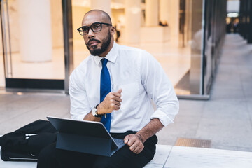 Pensive black manager thinking while working on tablet