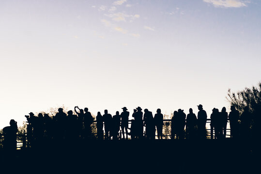 Silhouetted tourists taking photos during sunrise.