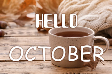 Hello October card. Cup of hot drink and autumn leaves on wooden table