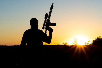 Fototapeta na wymiar Silhouette of a man with a weapon in his hands on a sunset background