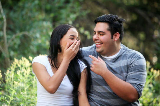 Hispanic couple outdoors laughing with each other