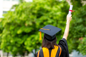 Graduates raise their hands to celebrate graduation with diplomas and pride and happiness.