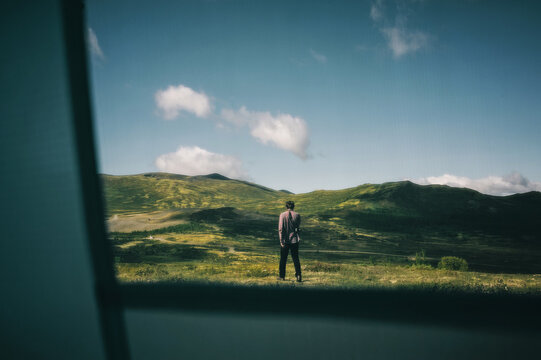 Into the Wild: Man Walking through Scandinavian Landscape, View through the Mosquito Net of a Tent