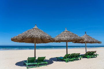 Tropical sand beach and summer sea water with blue sky and straw umbrella. Travel and nature concept