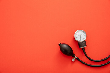 Medical sphygmomanometer on red color background, top view.