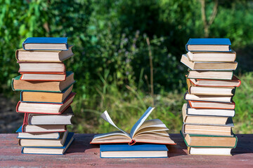 Stack of books on wooden table over nature background, outdoors