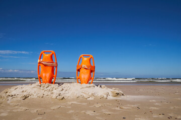 Closeup of some colorful rescue buoys in the sand of a beach in the Baltic sea.