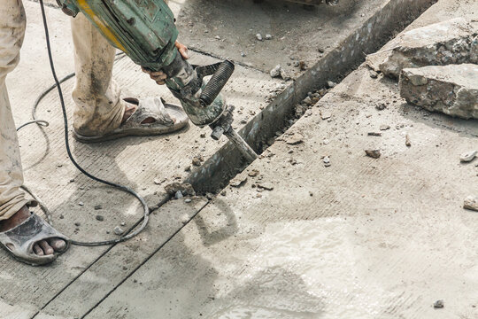 Construction worker using jackhammer drilling concrete surface