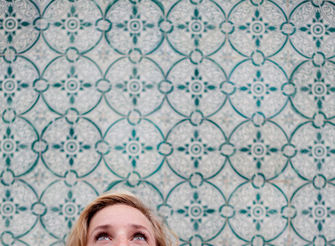 Young beautiful women looks up with clear bright eyes in front of a tiled wall
