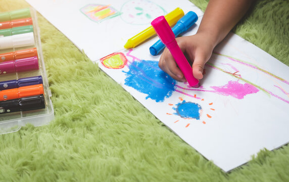 Child kid doing drawing picture with color crayons
