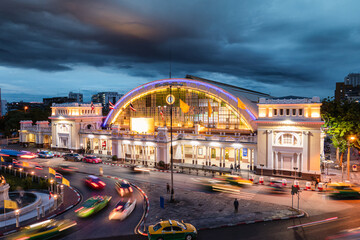Facade antique Hua Lamphong railway station illuminated with car and roundabout road in gloomy at...