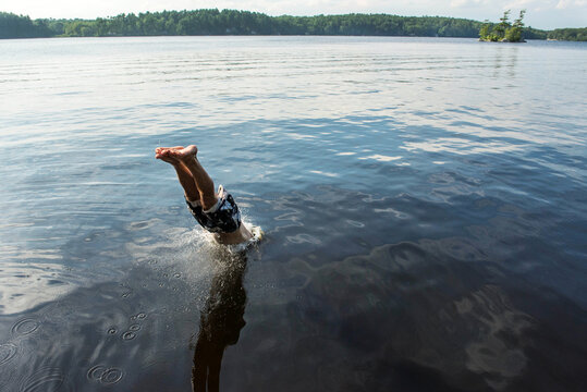 Man is halfway in the water as he dives into a lake